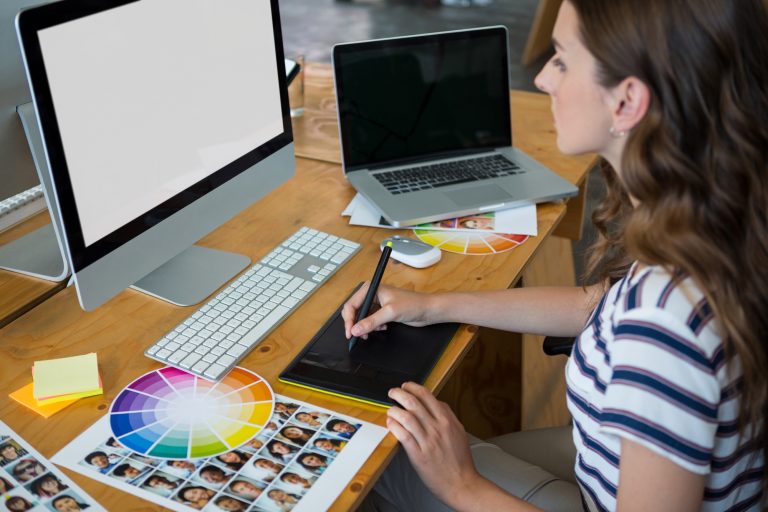 Female graphic designer using graphics tablet at desk