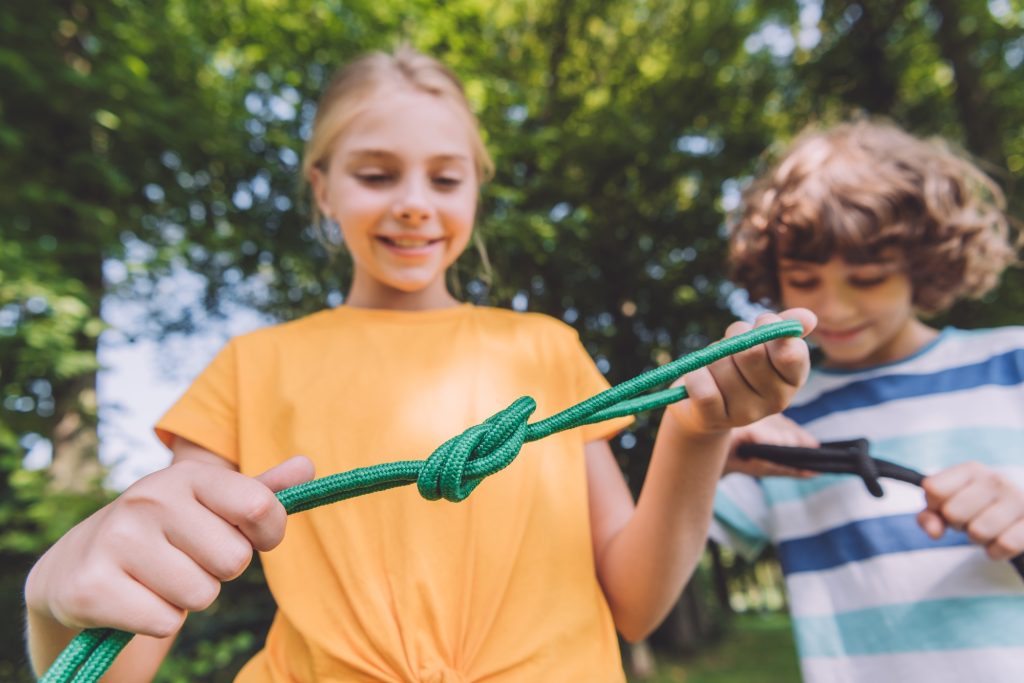 selective focus of happy kids holding ropes in park