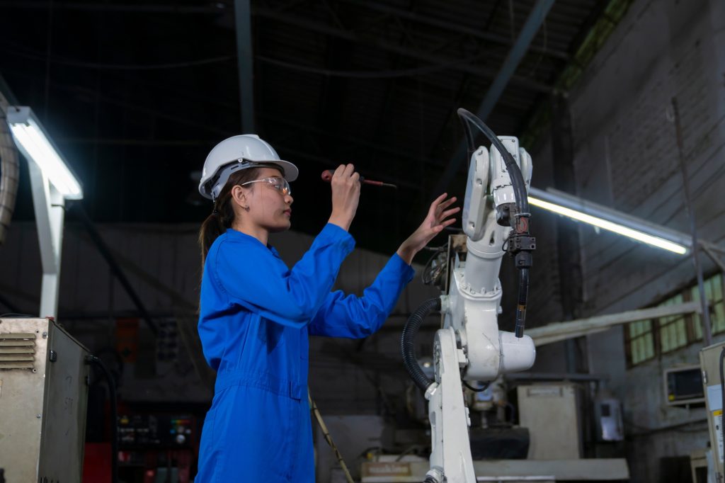 Woman mechanic repairing a robot machine.